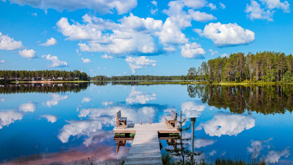 낮에는 푸른 하늘과 흰 구름 아래 호수에 있는 갈색 나무 선착장