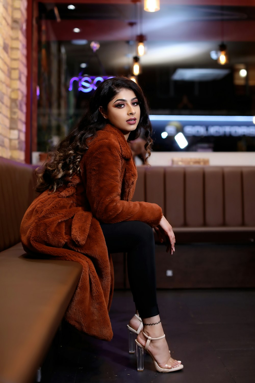 woman in brown fur coat sitting on brown wooden bench