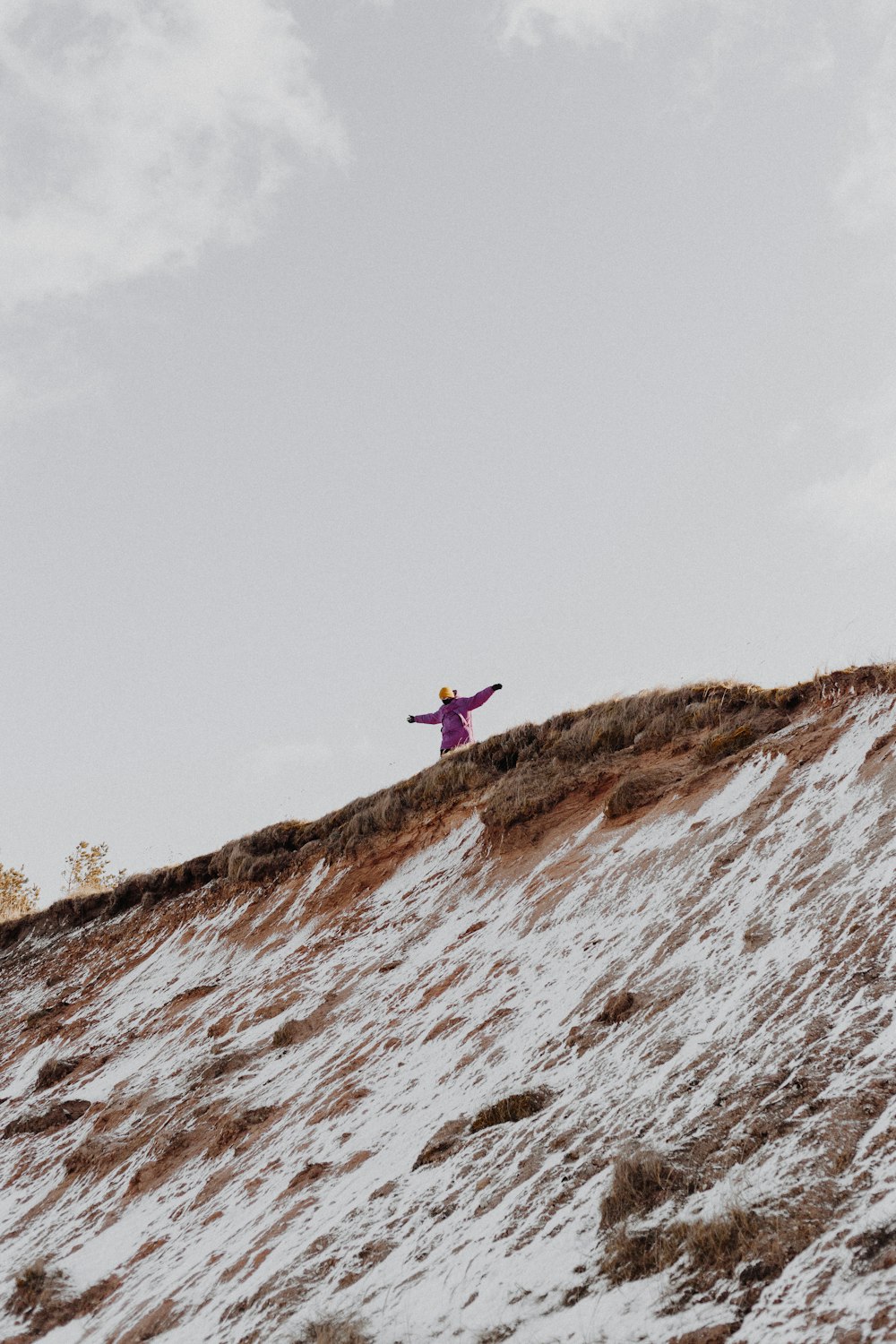 person in red jacket standing on brown rock mountain during daytime