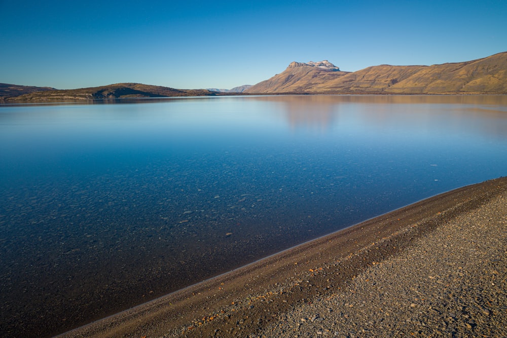 blue sea near brown mountain under blue sky during daytime