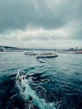 white and black boat on sea under white clouds during daytime
