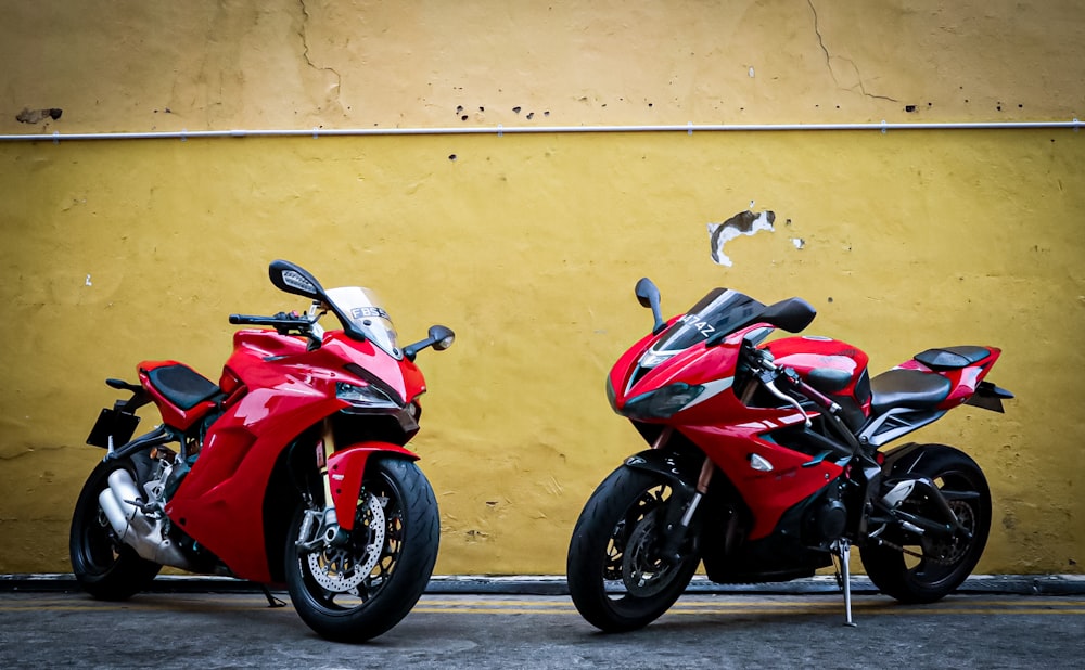 red and black sports bike parked beside white wall
