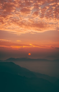 A breathtaking sunset over a mountain range, with warm hues painting the sky.
