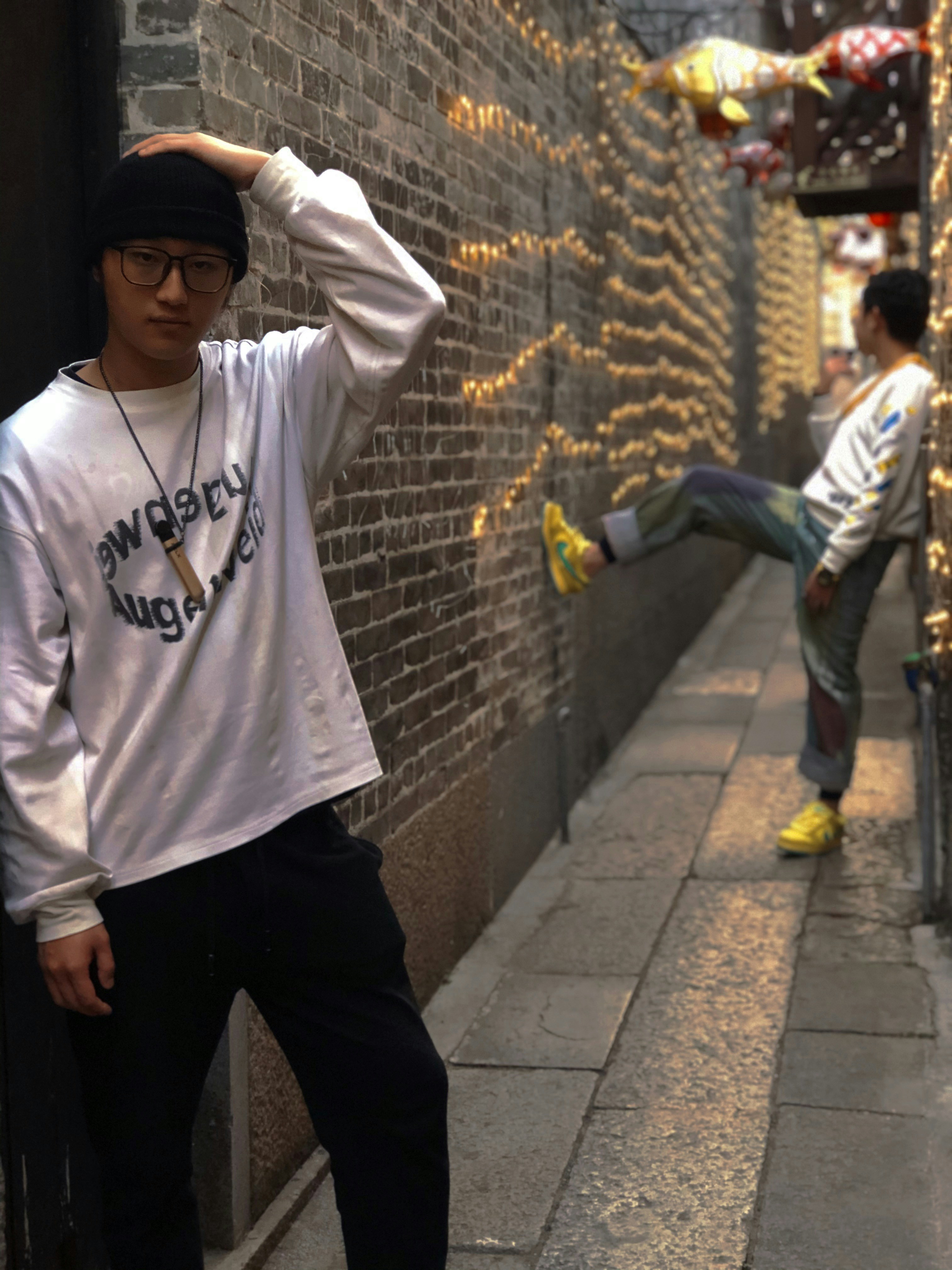 man in white and black hoodie and black pants standing on gray concrete pavement during daytime