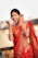 A joyful woman wearing a beautifully draped saree, smiling while admiring herself in a mirror.