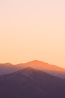Golden sunlight casting warm hues over a quiet mountain range at sunset.