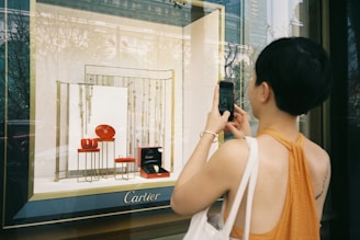 woman in white tank top holding black smartphone