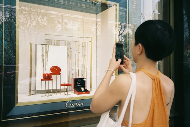 woman in white tank top holding black smartphone