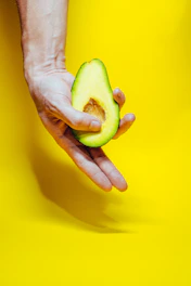 person holding green fruit on yellow surface