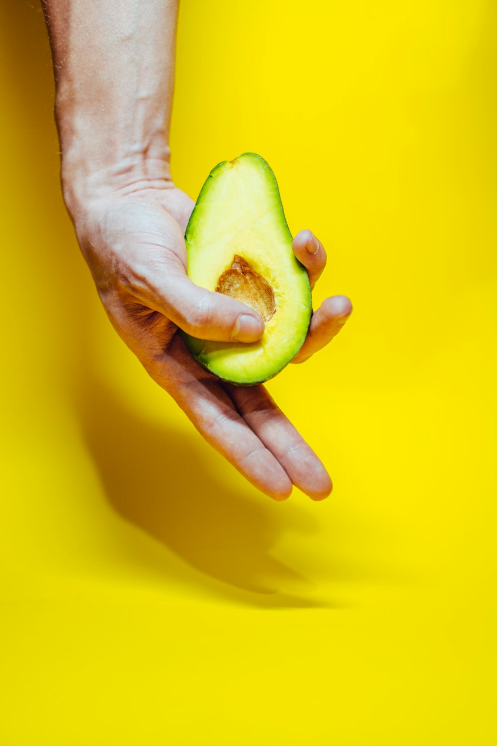 person holding green fruit on yellow surface