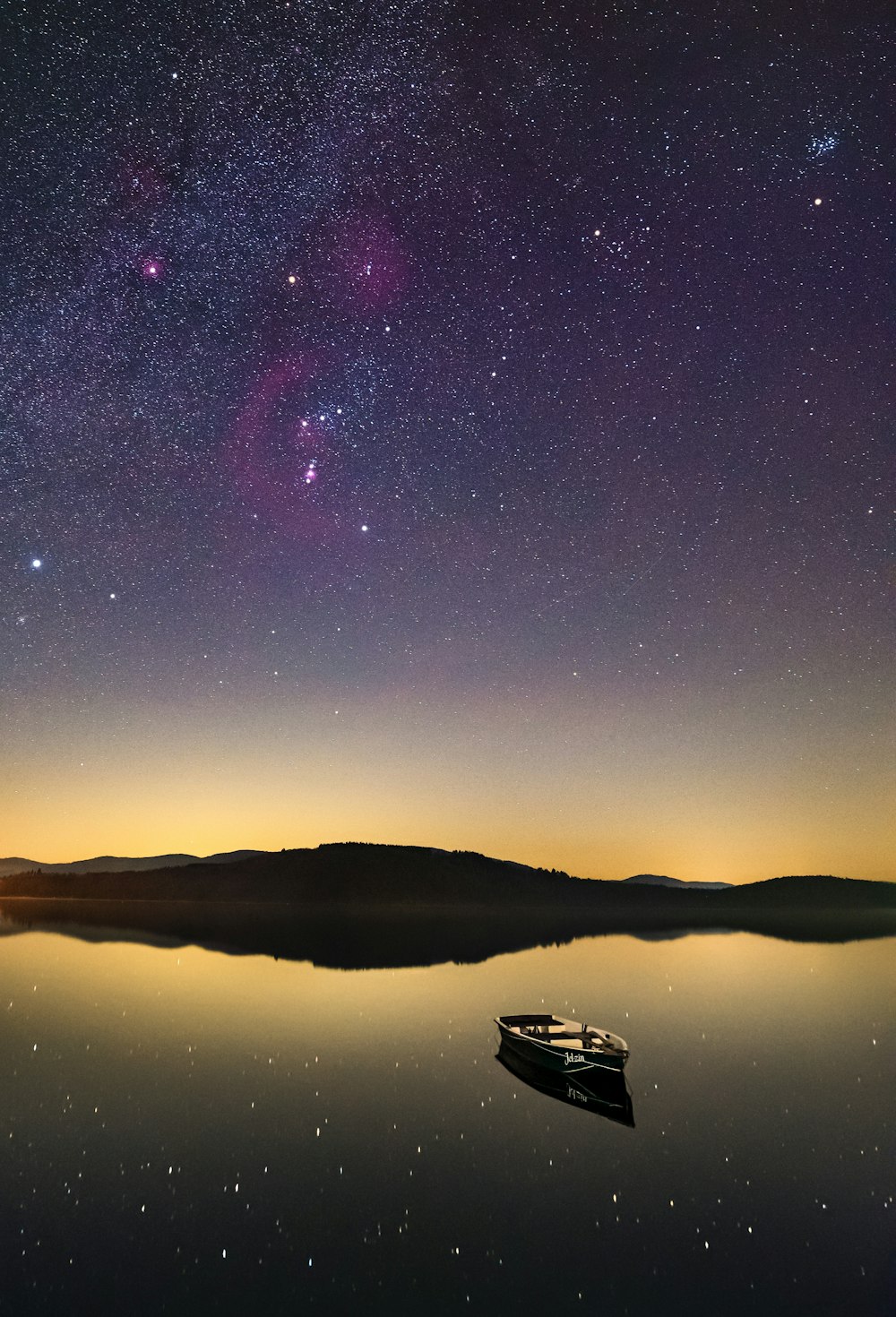 Barca bianca sull'acqua sotto la notte stellata