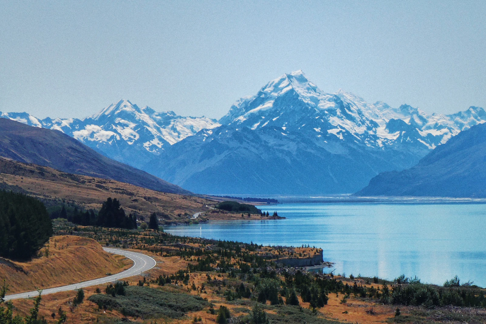 A lake fringed with trees below a snow-covered peak in New Zealand
