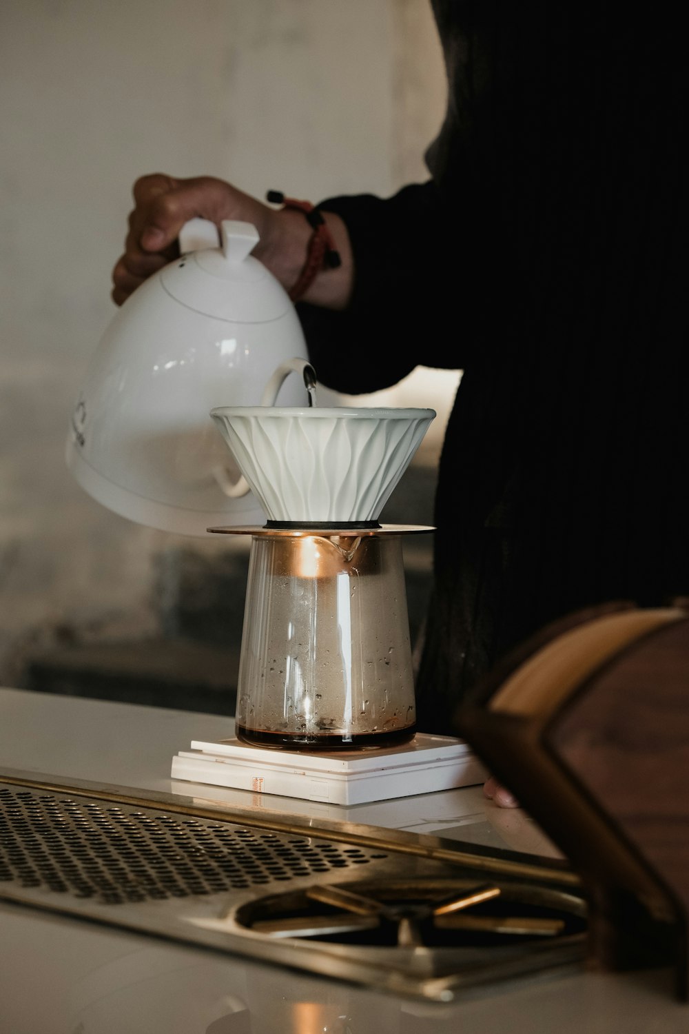 a person pouring coffee into a pot on top of a stove