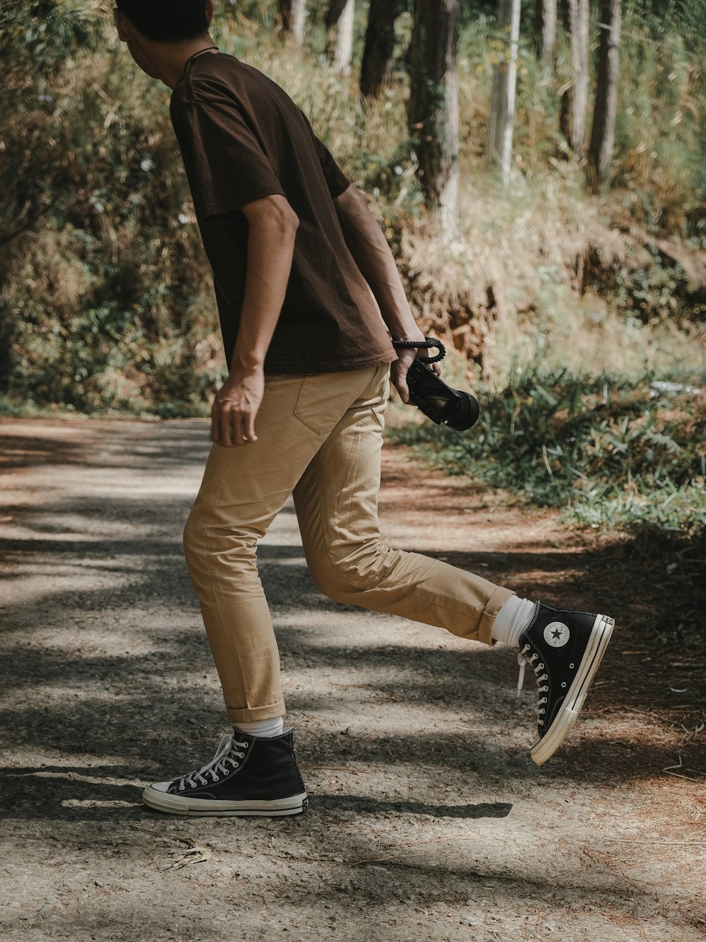 a man walking down a dirt road holding a camera