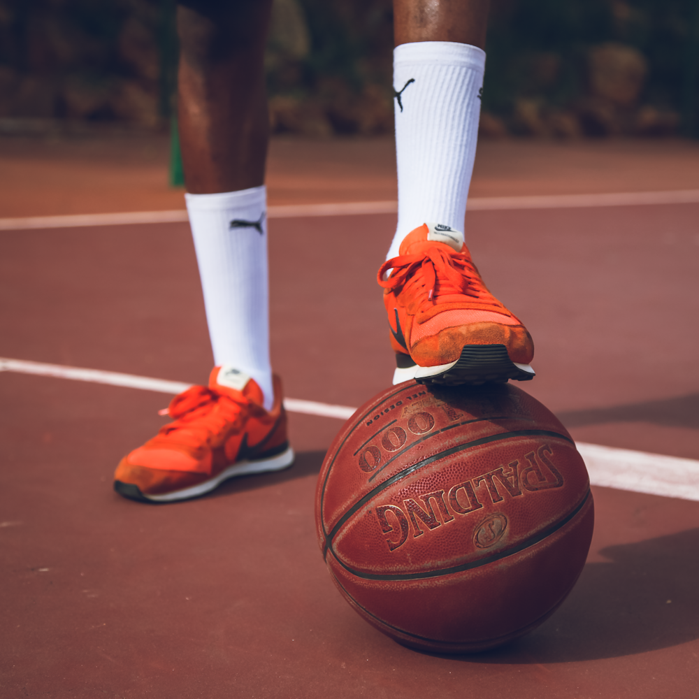 a man standing on top of a basketball on a court