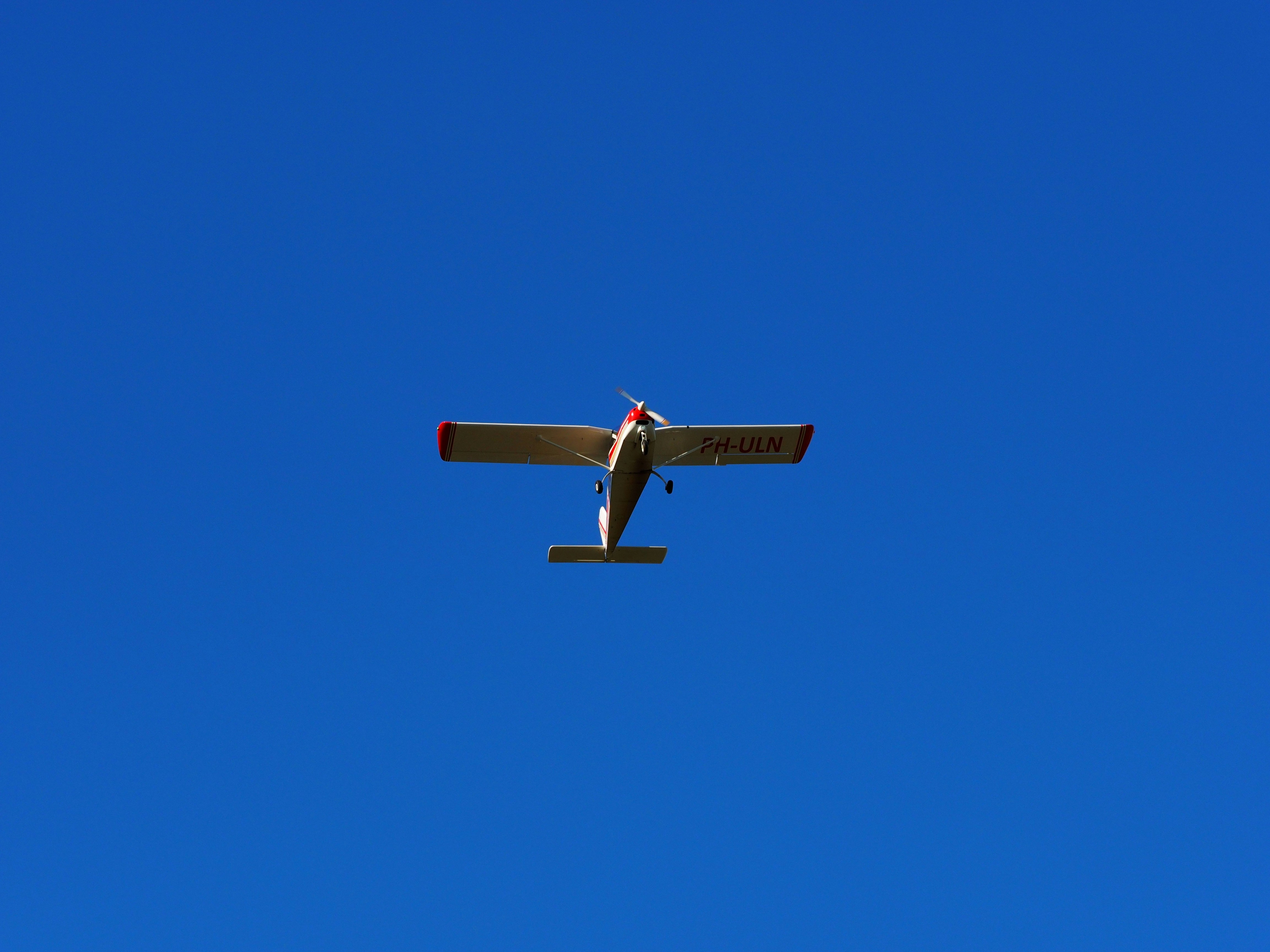 blue and white plane flying under blue sky during daytime, 