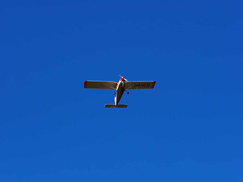 blue and white plane flying under blue sky during daytime