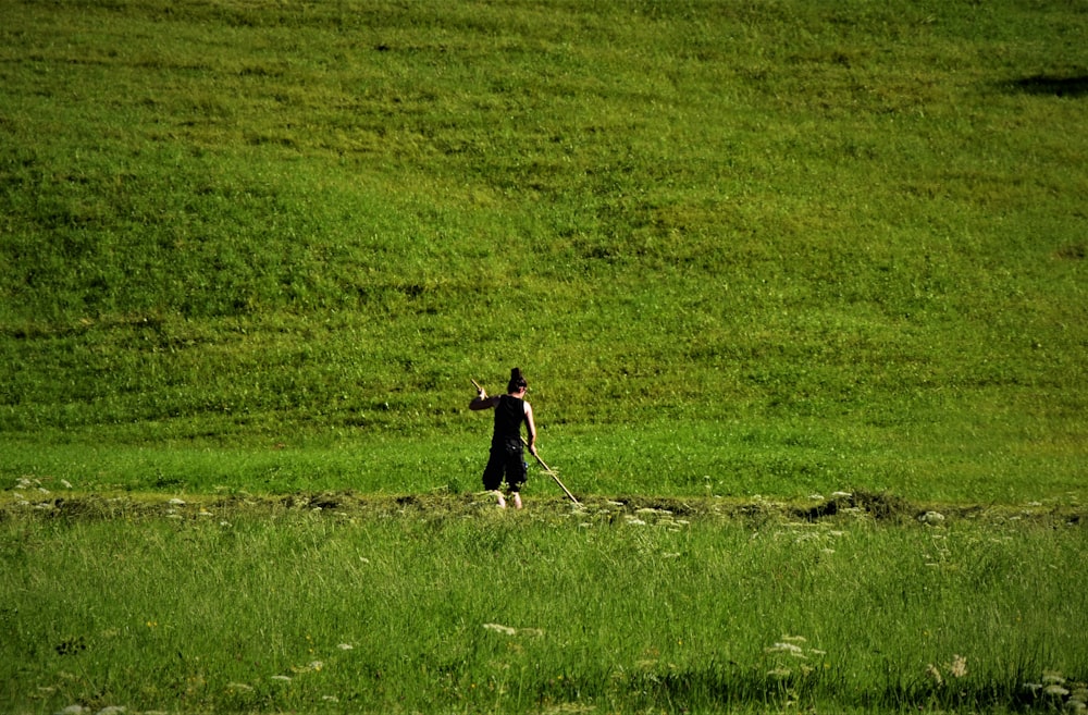 person in black shirt walking on green grass field during daytime