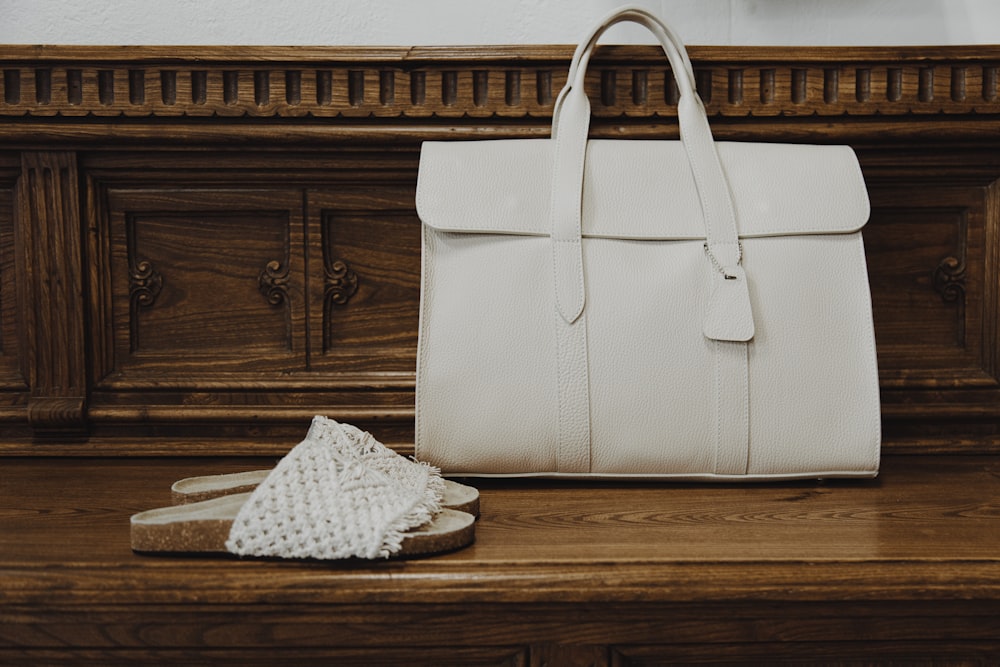 white leather handbag on brown wooden table