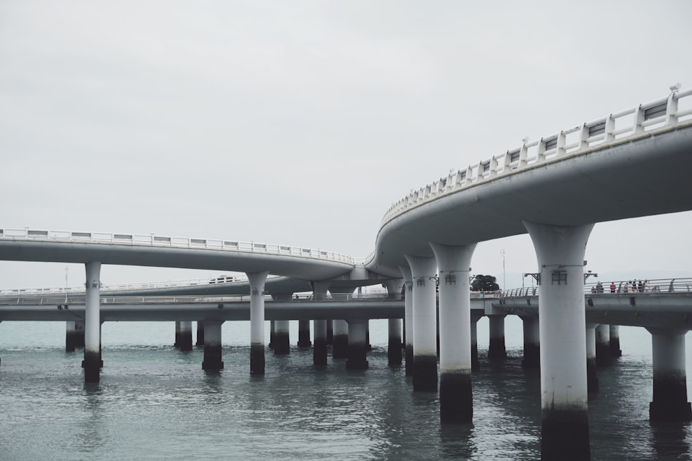 white concrete bridge over blue sea under white sky during daytime