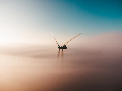 wind turbine emerging from fog at sunrise
