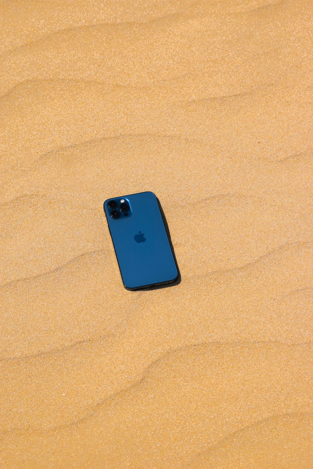 Coque iPhone bleue sur sable brun