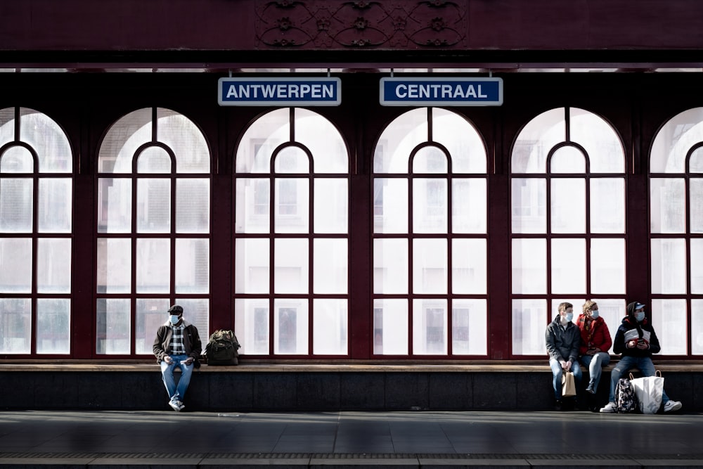 2 men sitting on bench in front of building