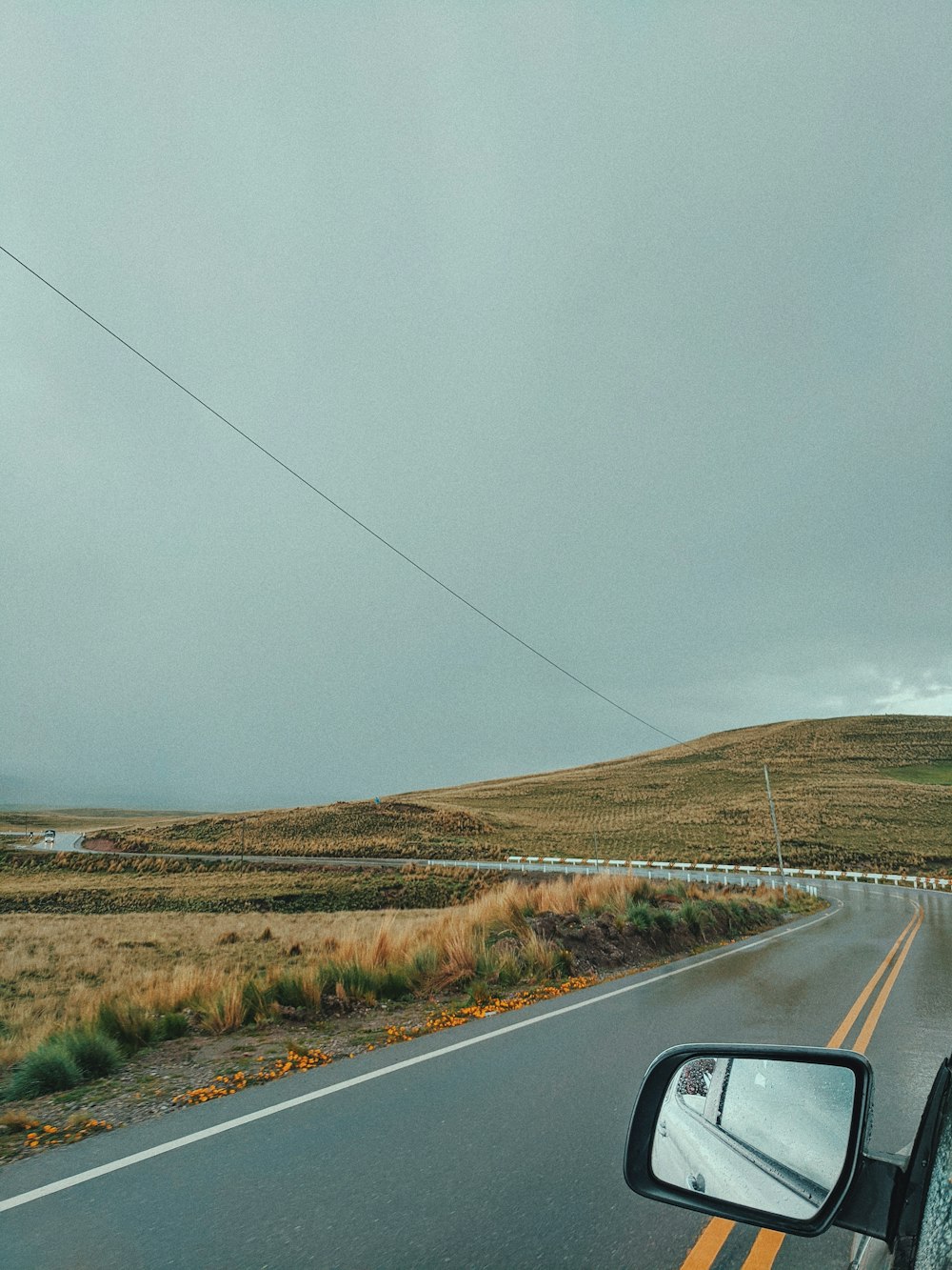 car on road near brown grass field during daytime