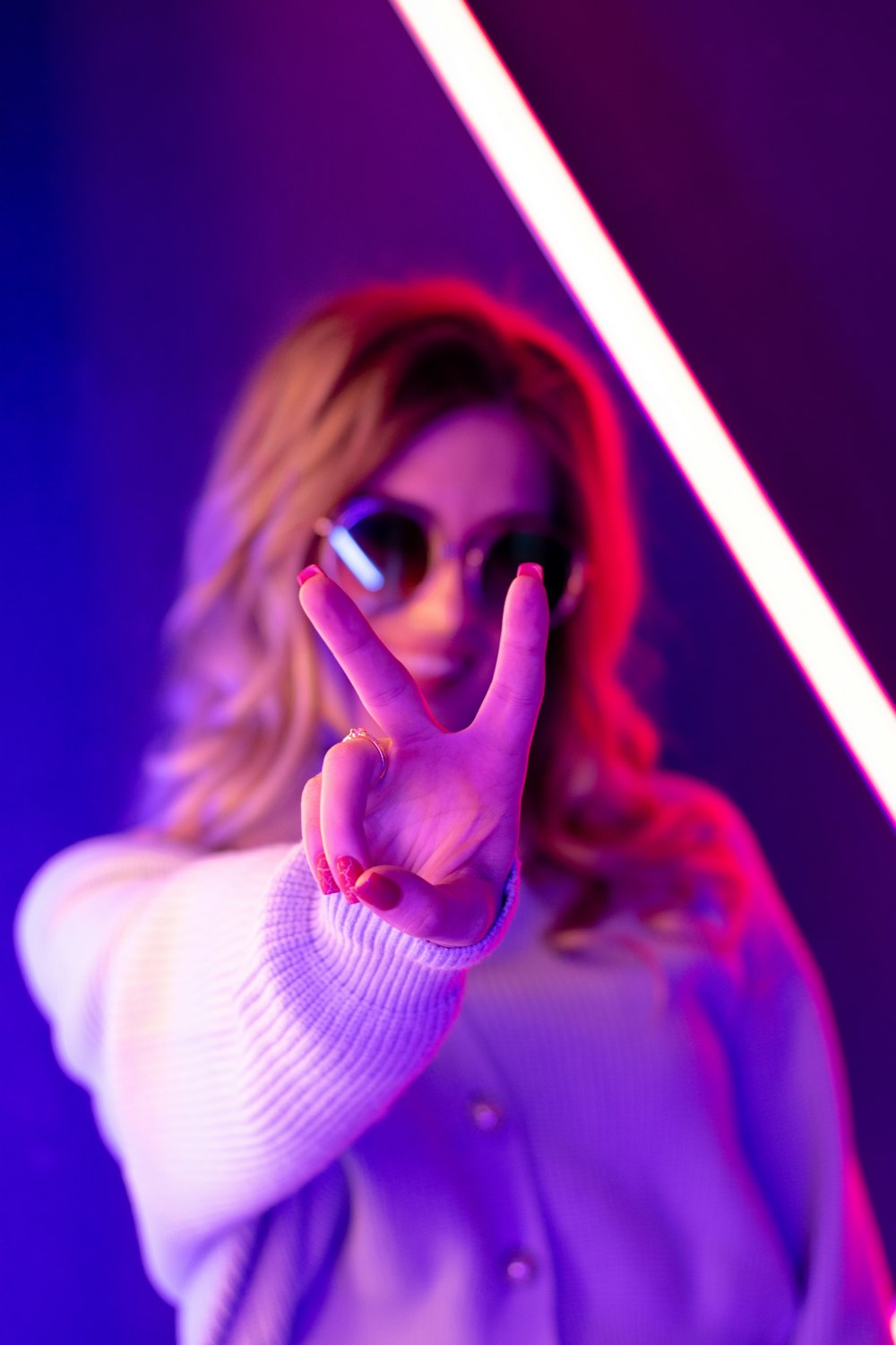 woman in white sweater holding her sunglasses