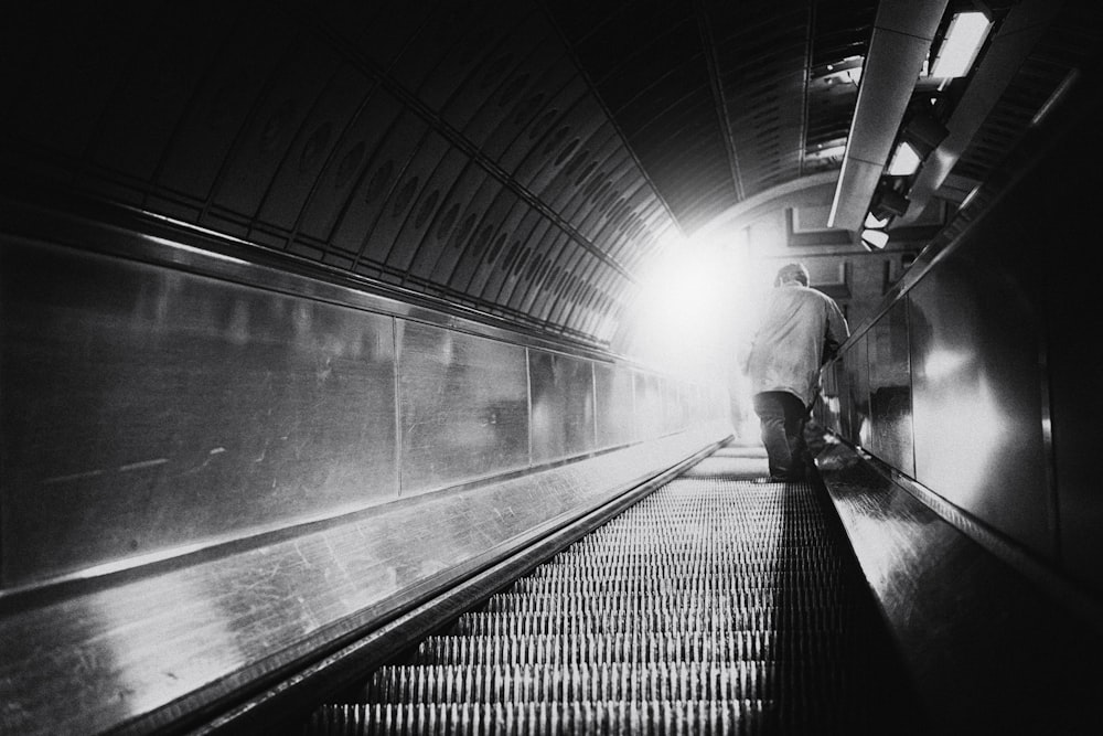 man in black jacket walking on escalator