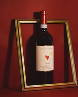 a bottle of wine sitting in front of a picture frame