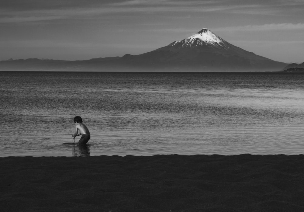 grayscale photo of man and woman walking on beach