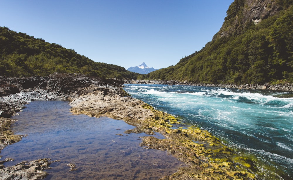 green mountain beside body of water during daytime