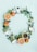 A circular arrangement of fresh fruits and natural elements including apples, kiwis, grapefruit halves, coconuts, leaves, and blackberries. There is also a tea cup filled with green tea and a dropper bottle. The items are placed on a light mint background, giving a fresh and natural look.