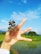 A thoughtful man holding a small sapling against a backdrop of green hills.