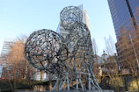 An abstract sculpture made of smooth, curved wood set against a New York City backdrop.