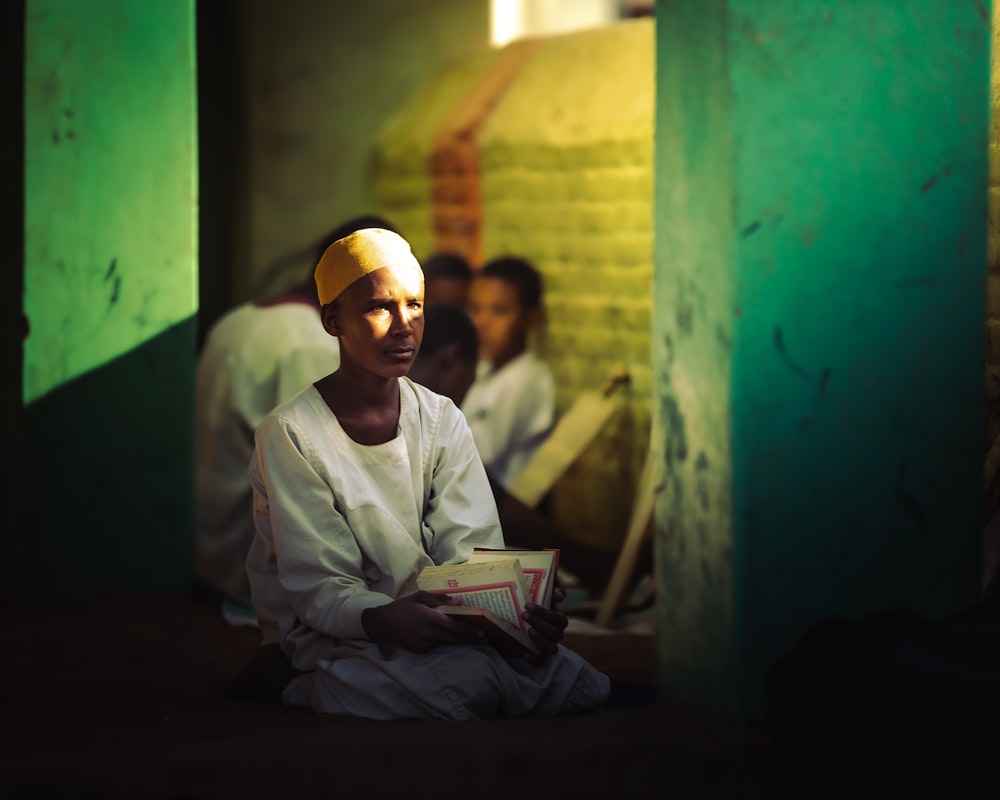 man in white thobe sitting on floor