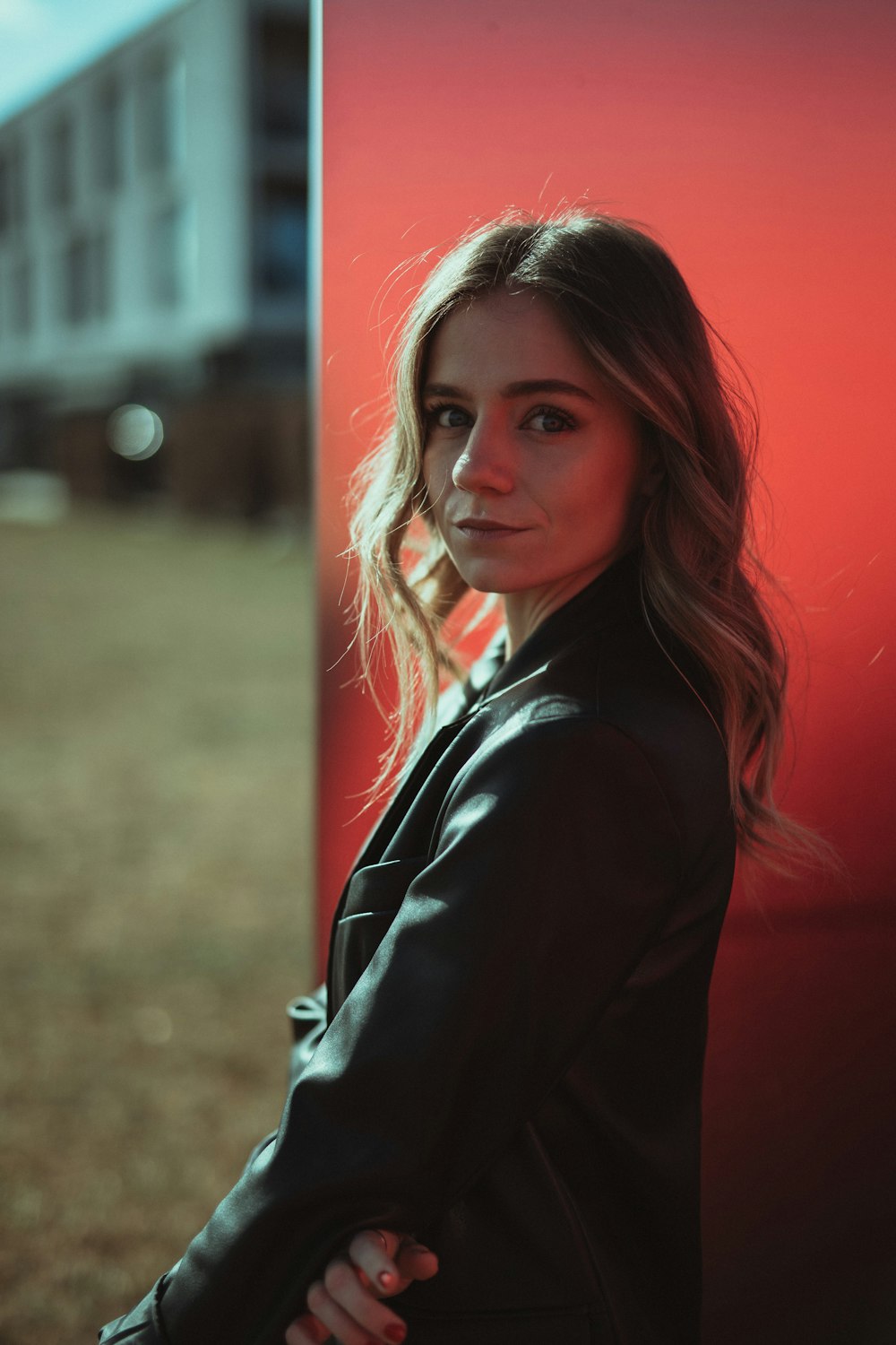 woman in black blazer standing beside red wall