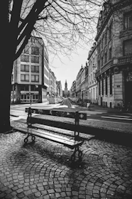 An atmospheric black-and-white photo of a quiet city street at dawn.