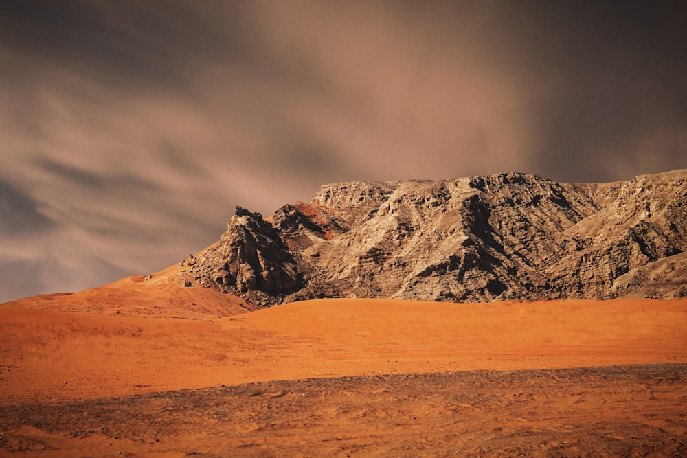 brown and white mountain under gray sky