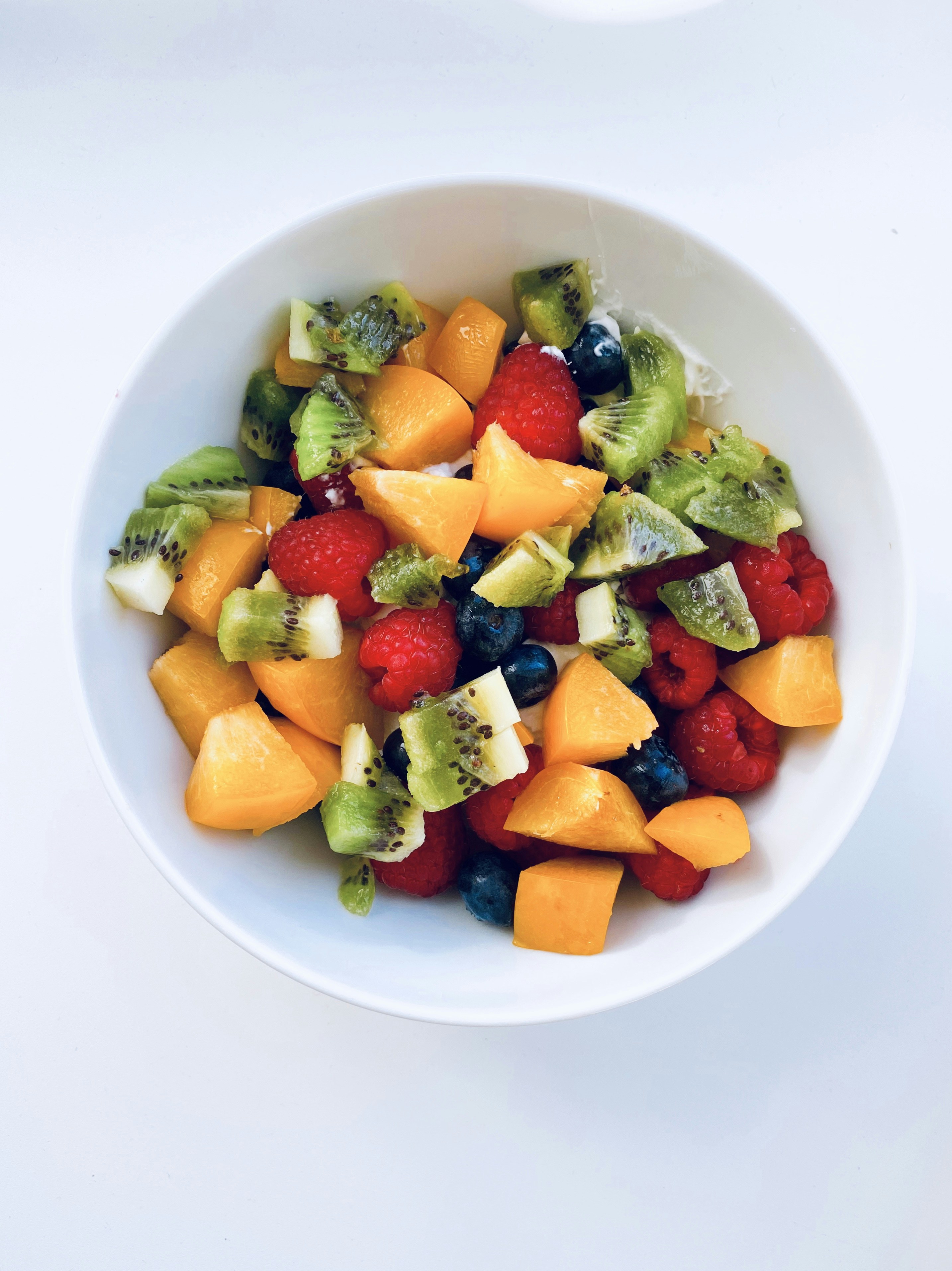 Fresh orange juice glass alongside a colorful fruit salad bowl