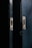 Two metal doors with a dark, weathered texture are slightly ajar, revealing a narrow gap of darkness between them. The doors have metallic slots and screws, suggesting they may belong to a cabinet or a locker.