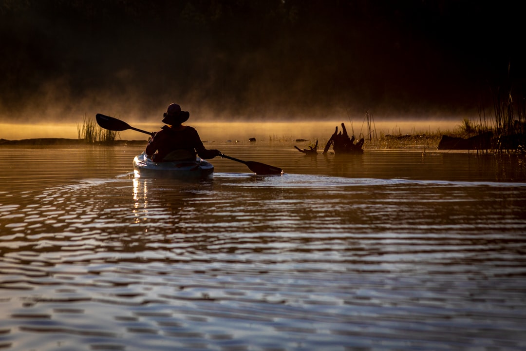 man riding on kayak on body of water during daytime