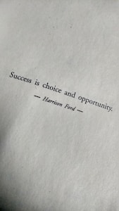 Text on a textured paper background reads 'Success is choice and opportunity' attributed to Harrison Ford.