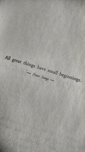 A motivational quote printed in black text on a textured white paper. The quote reads: 'All great things have small beginnings.' The author's name, Peter Senge, is printed below the quote, centered and flanked by horizontal lines.