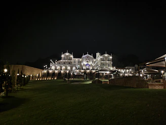 A dramatic nighttime shot of La Mansión Blanco illuminated against a dark sky, capturing its mysterious and elegant atmosphere.