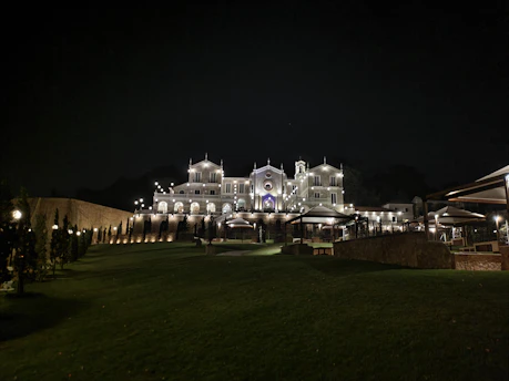 A dramatic nighttime shot of La Mansión Blanco illuminated against a dark sky, capturing its mysterious and elegant atmosphere.