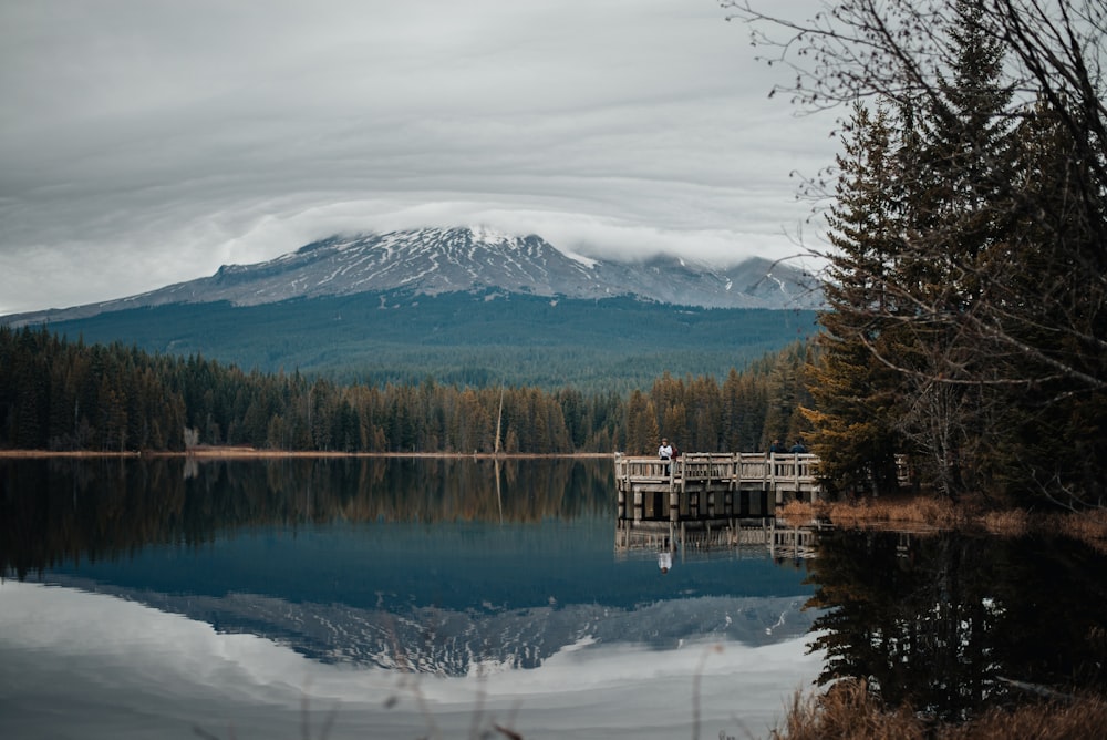 Braunes Holzdock am See in der Nähe des schneebedeckten Berges tagsüber