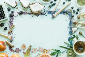 A vibrant flat lay of natural cosmetic products with fresh flowers and leaves on a wooden table.