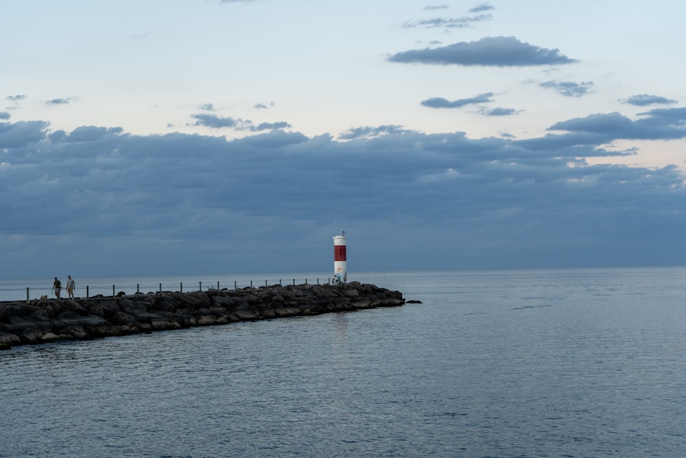 white and red lighthouse near body of water during daytime